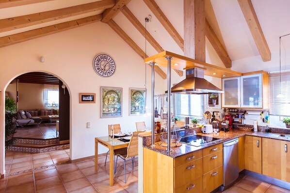 Uma cozinha com armários de madeira, uma ilha central e uma área de jantar com cadeiras e mesa.