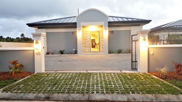 Stylish entrance with a stone accent wall and glass door, set amidst a beautifully manicured lawn.