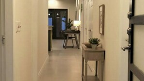Un pasillo con un escritorio y una planta, que conduce a una habitación con una puerta.