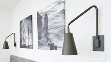 Eine Wand mit drei schwarzen Wandlampen und zwei Schwarz-Weiß-Fotografien.