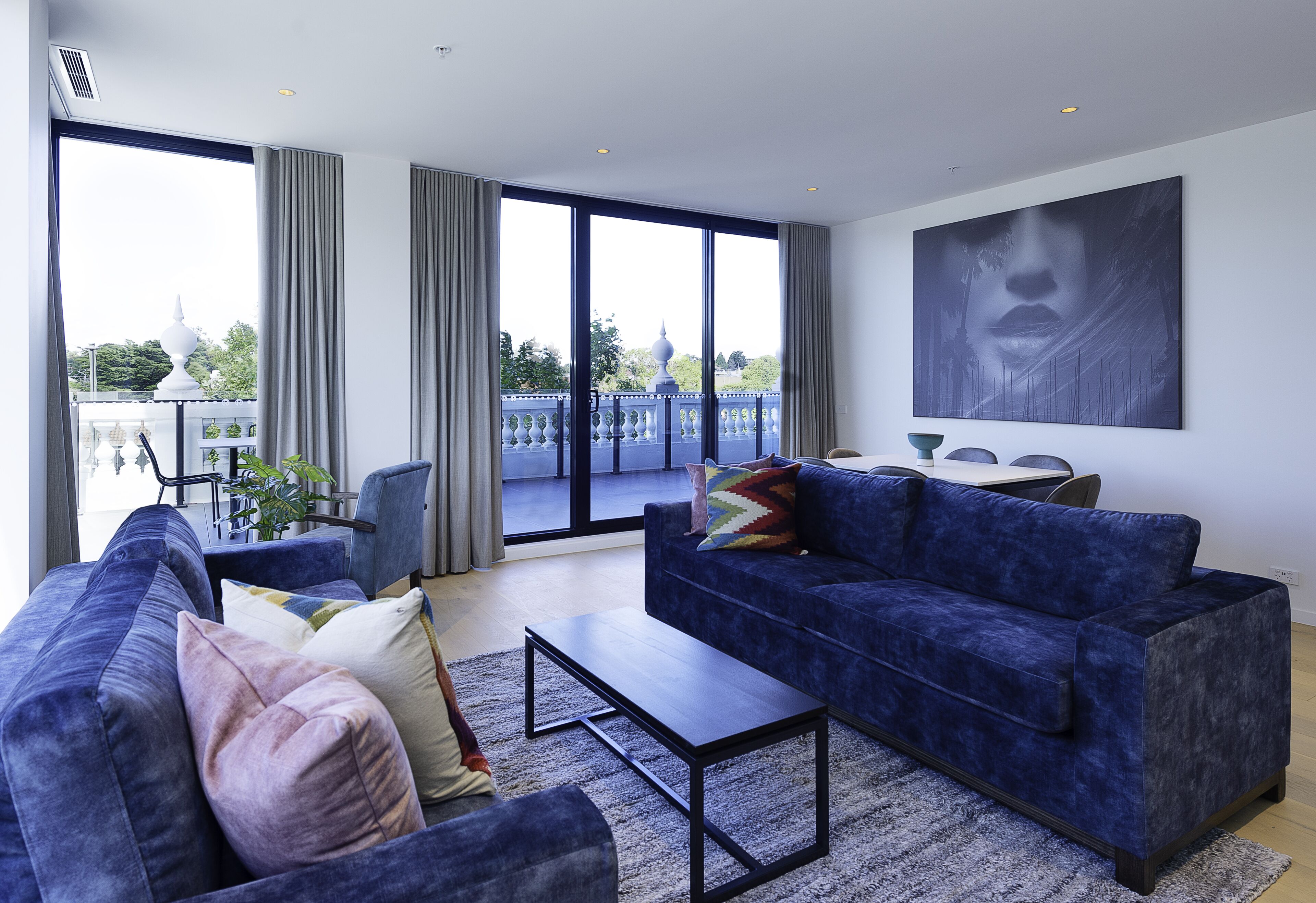 Una sala de estar moderna con un sofá azul, una mesa de centro y un ventanal con cortinas.
