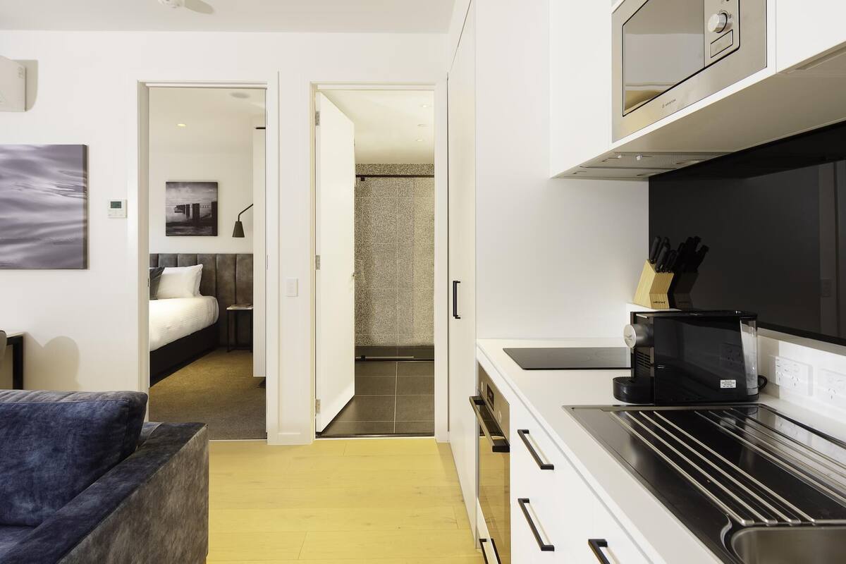 A compact hotel room with a kitchenette, a bed, and a bathroom.
