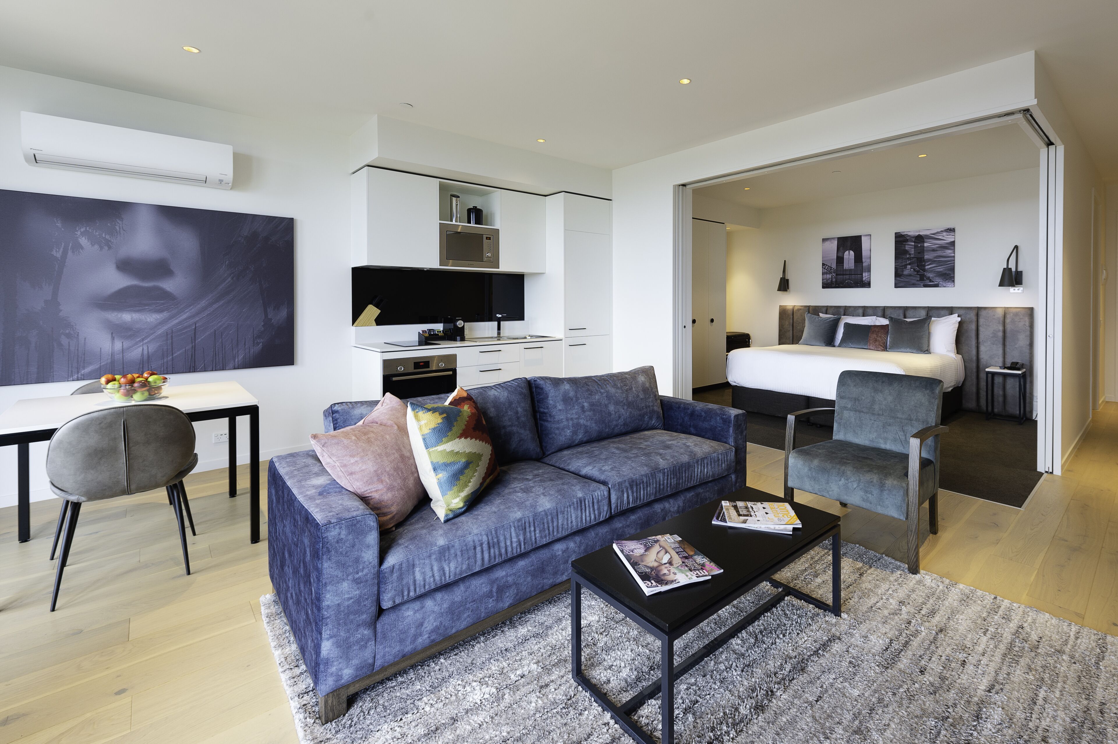 A modern living room with a sofa, coffee table, and a dining area with a TV.