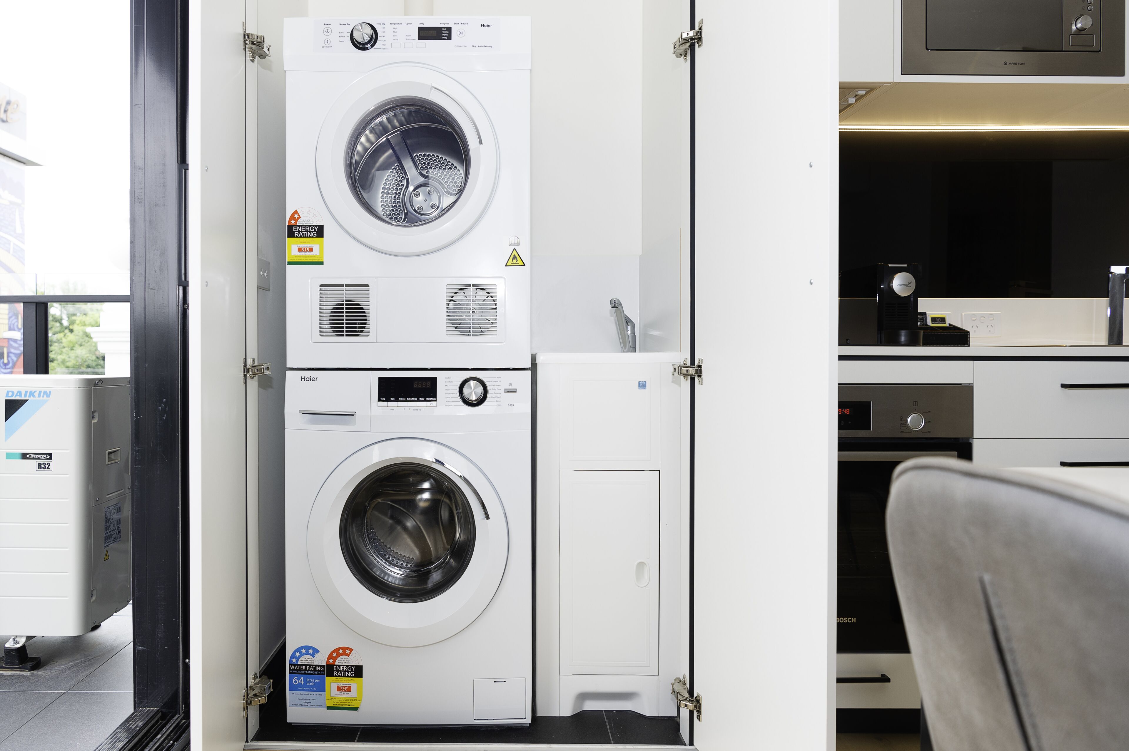 A laundry area with two stacked washing machines, a dryer, and a microwave.