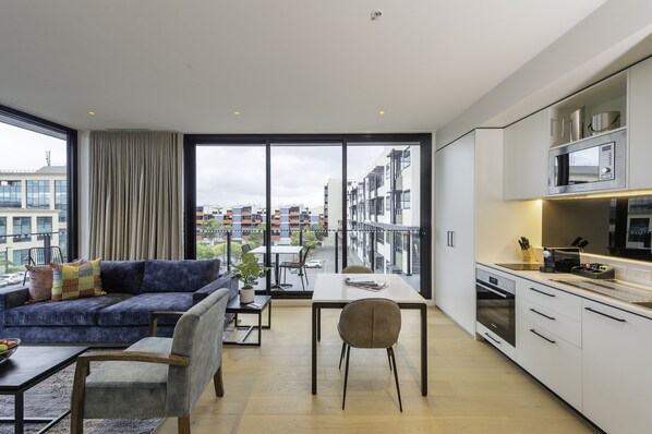 A modern apartment with a balcony, a dining area, and a kitchenette. - Oaks R Suites Geelong (Geelong)