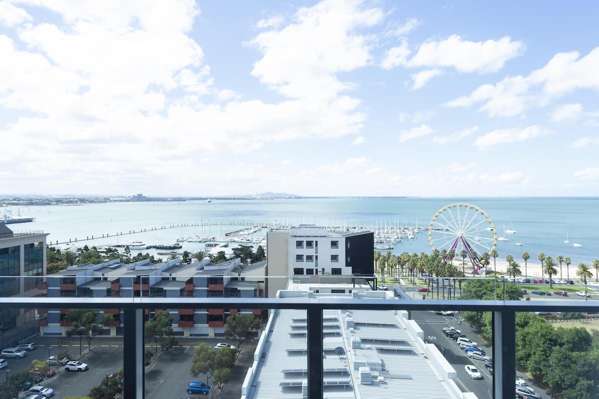 A view from a balcony overlooking a marina with a Ferris wheel, boats, and a clear sky.
