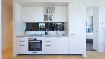 A modern kitchen with white cabinetry, a built-in microwave, and an oven.