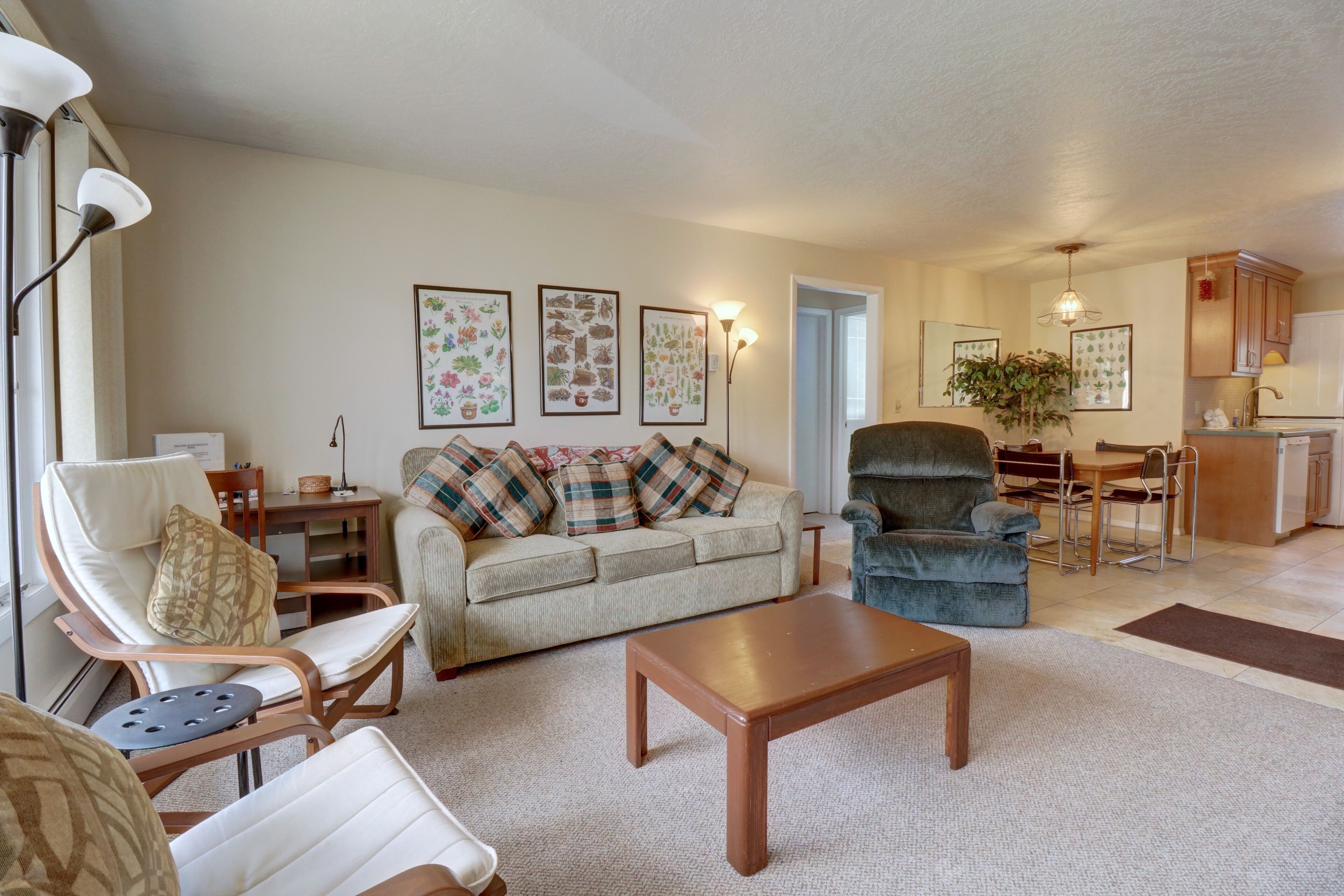 A living room with a sofa, armchairs, a coffee table, and a dining area with a table and chairs.