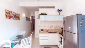 A compact kitchen with a refrigerator, a sink, and a dining area with chairs and a table.