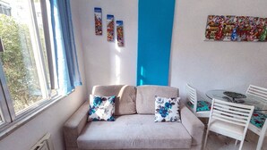 A living room with a sofa, two pillows, a small table, and a chair.