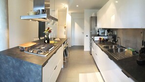 A modern kitchen with a gas stove, stainless steel appliances, and a variety of utensils.