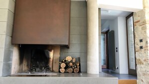 A modern fireplace with a large, dark metal cover, a log display, and a stone column.