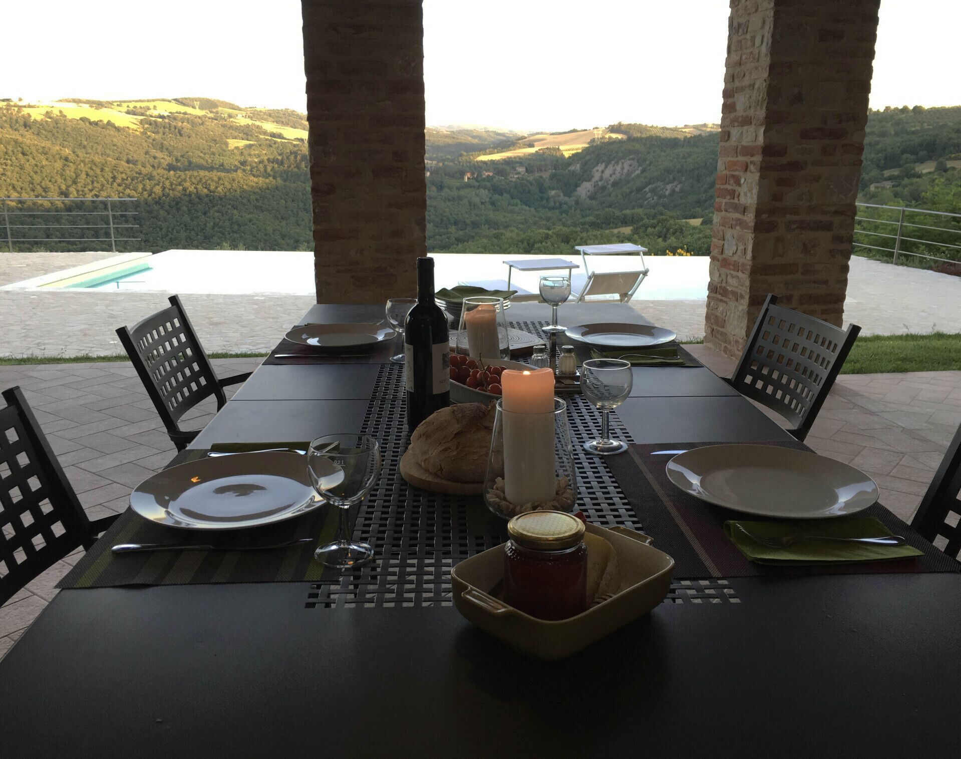 Mesa posta para dois, com vela, garrafa de vinho e pão, com vista panorâmica.