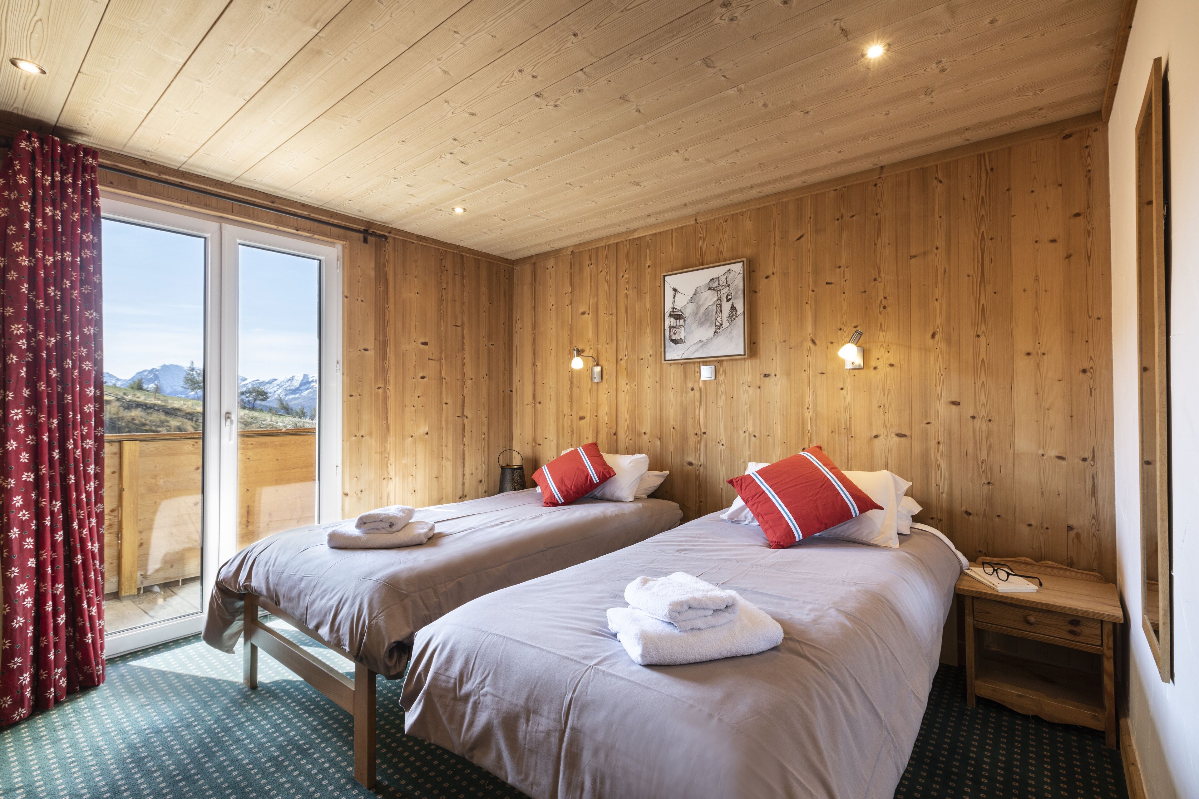 Ein Zimmer mit zwei Betten, Holzwänden, einem großen Fenster und Bergblick.