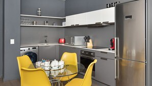 Cozinha compacta com máquina de lavar, micro-ondas e frigorífico em aço inoxidável.