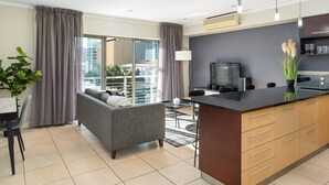 Un appartement moderne avec un canapé gris, une table à manger et un coin cuisine.