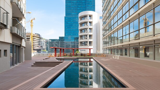 Un bâtiment moderne doté d’un bassin d’eau réfléchissant, de grandes fenêtres et d’une enseigne « Investec » bien visible.