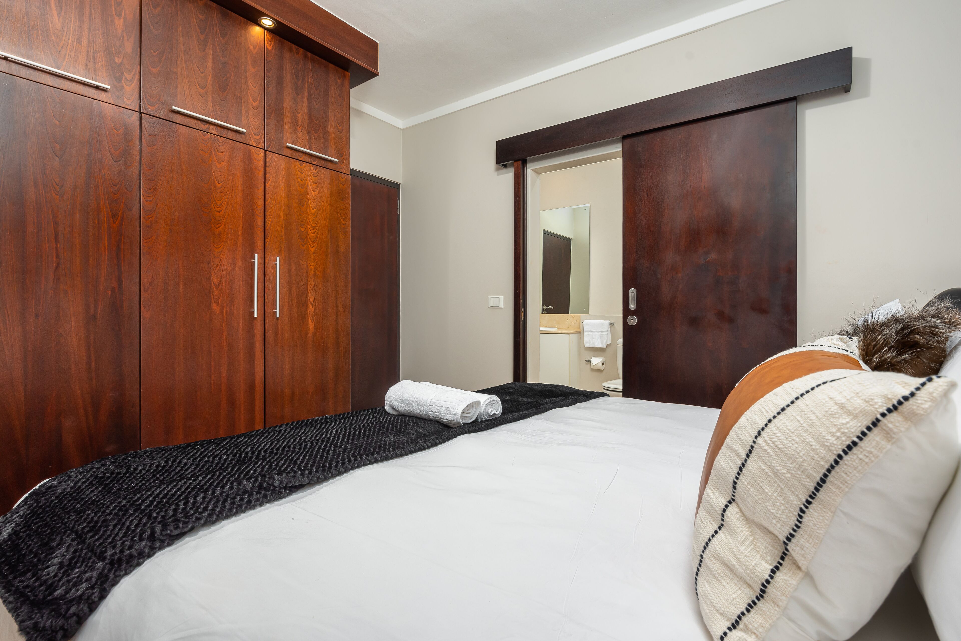 A bedroom with a large bed, wooden wardrobe, and a sliding door closet.