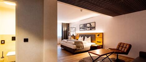 Una habitación de hotel moderna con una cama grande, un escritorio y un sillón cómodo.