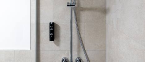 Een moderne douche met een handdouche en bedieningspaneel aan de muur.