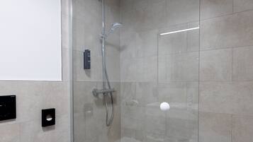 Ein modernes Badezimmer mit einer Duschkabine, einem weißen Waschbecken und einer Toilette.
