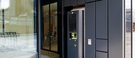 A modern building entrance with a glass door and a digital payment kiosk.