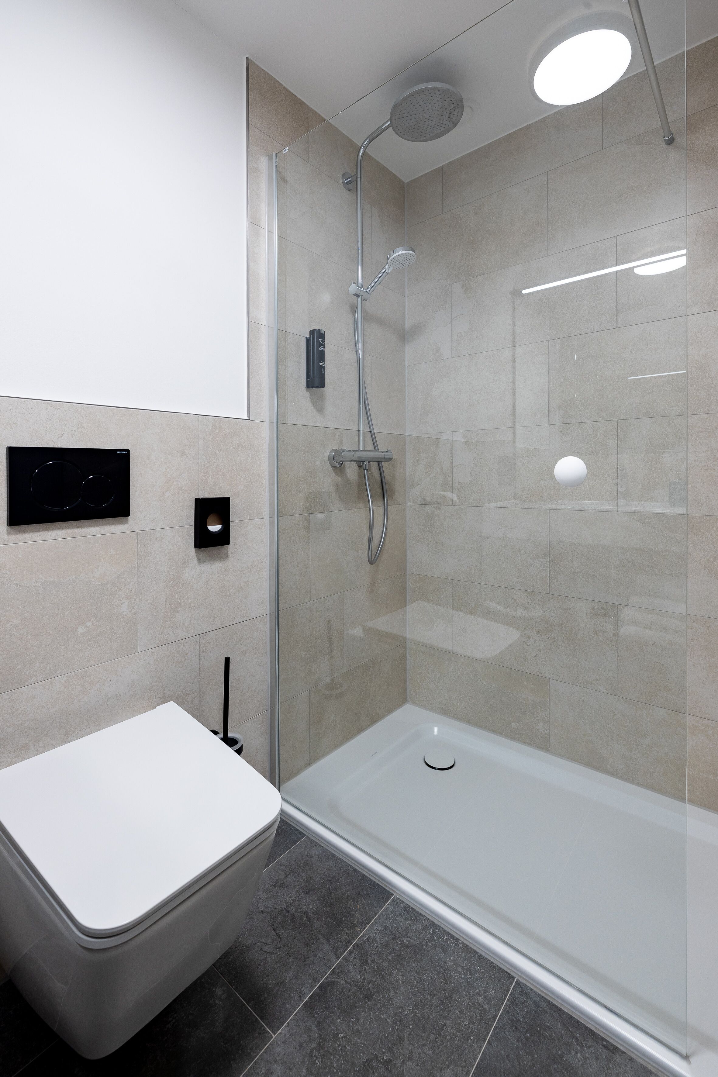 Un baño moderno con cabina de ducha de vidrio, inodoro blanco y diseño elegante.