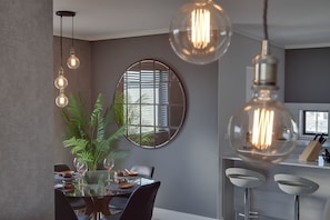 Enjoy meals for two at a stylish dining area with a glass table and comfortable bar stools.