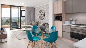 A modern apartment with a dining area, kitchen, and a balcony with a city view. - Waters Edge 503 (Cape Town)
