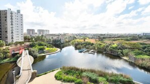 A river with a bridge, surrounded by greenery and buildings. - Waters Edge 503 (Cape Town)