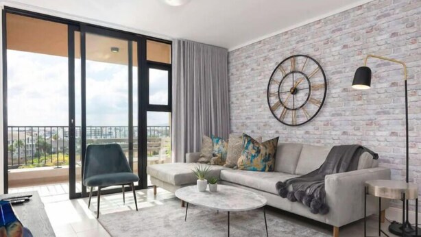 A modern living room with a sofa, coffee table, and a large window with a view. - Waters Edge 503 (Cape Town)