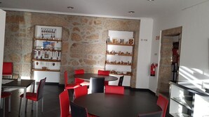 A dining area with a stone wall, red chairs, and a round table. - Casa Dr. Saba (Belmonte, Portugal)