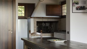 Une cuisine dotée d’un plan de travail en bois, d’une cuisinière encastrée et d’une cheminée en briques.