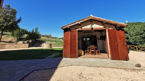 Un bâtiment rustique en bois, doté d’un toit en tuiles, d’un mur en pierre et d’un chemin de gravier menant à l’entrée.