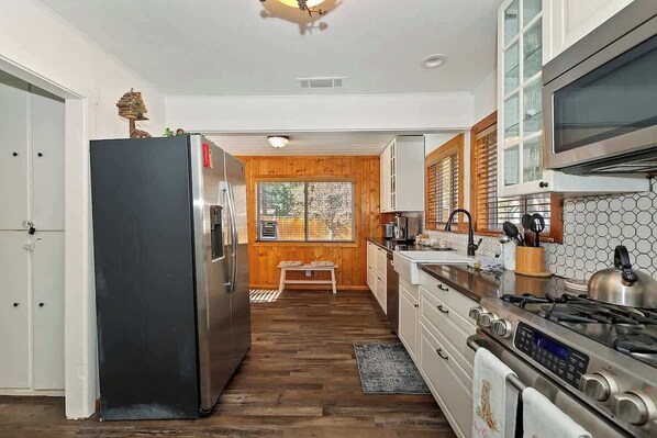 A modern kitchen with a stainless steel refrigerator, a built-in oven, and a microwave.