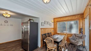 A compact kitchen with a refrigerator, wooden dining table, and chairs. - Red Robin W  Hot Tub Retreat Near Big Bear Lake (Big Bear Lake)
