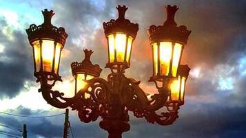 Eine Straßenlaterne mit drei Leuchten vor einem bewölkten Himmel.