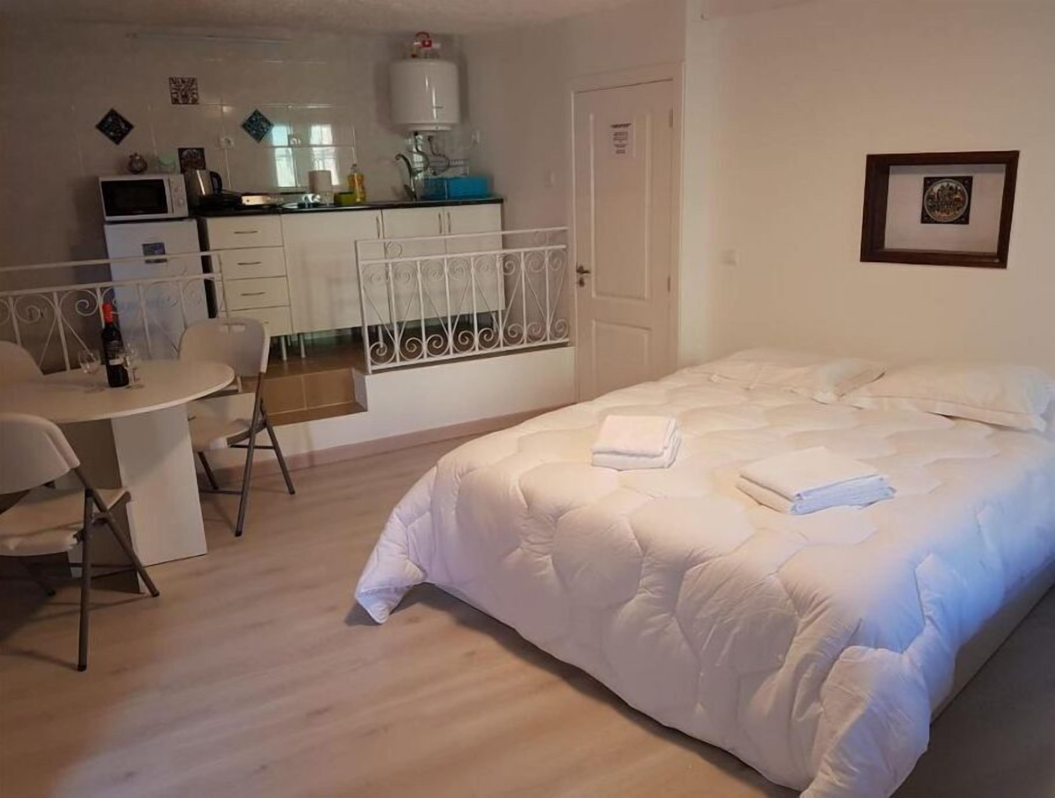 Een slaapkamer met een bed, een klein bureau en een kitchenette.