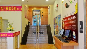 Zona de recepción con una escalera que sube al segundo piso, mostrador de recepción y un puesto de computadoras.