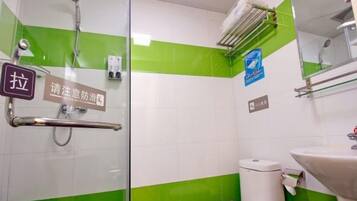 Casa de banho com chuveiro, sanita e lavatório. Apresenta azulejos verdes e brancos, um corrimão e um sinal com caracteres chineses.