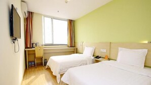 Une chambre d’hôtel avec deux lits, un bureau avec une chaise, une télévision et une fenêtre avec des rideaux.