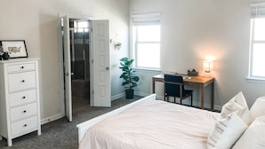 Une chambre à coucher comprenant un lit, un bureau, une chaise, une commode et une porte donnant sur un placard.