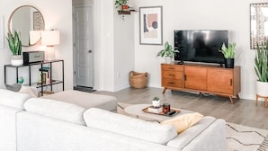 Un salon moderne avec un canapé blanc, un meuble en bois, un téléviseur et un ventilateur de plafond.