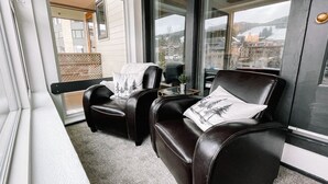 A room with two leather armchairs, a small table, and a window with a view of buildings and trees. - 🔥 3 Min Walk to Lift | Center Village | Views + Parking (Frisco)