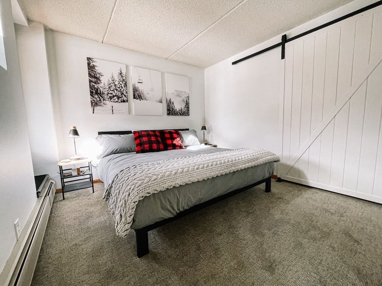 A bedroom with a bed, a nightstand, a lamp, and wall art.
