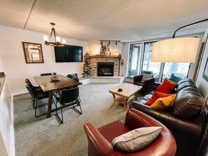 Cozy living space with a fireplace, dining area, and seating area featuring a leather couch.