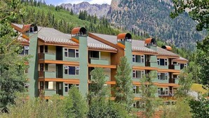 A multi-story hotel with balconies, set against a mountainous backdrop. - 🔥 3 Min Walk to Lift | Center Village | Views + Parking (Frisco)