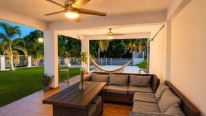 A covered outdoor seating area with wicker furniture, a hammock, and a ceiling fan. - Palm's Bohemian House with Private Pool (Aguada)