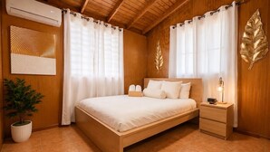 A wooden-paneled bedroom with a bed, curtains, a bedside lamp, and a wall-mounted air conditioner. - Palm's Bohemian House with Private Pool (Aguada)