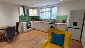 A compact kitchen with a dining area, a washing machine, and a refrigerator. - Garland Stylish Apartment 2 In Greater London (Upper Belvedere, Kent)